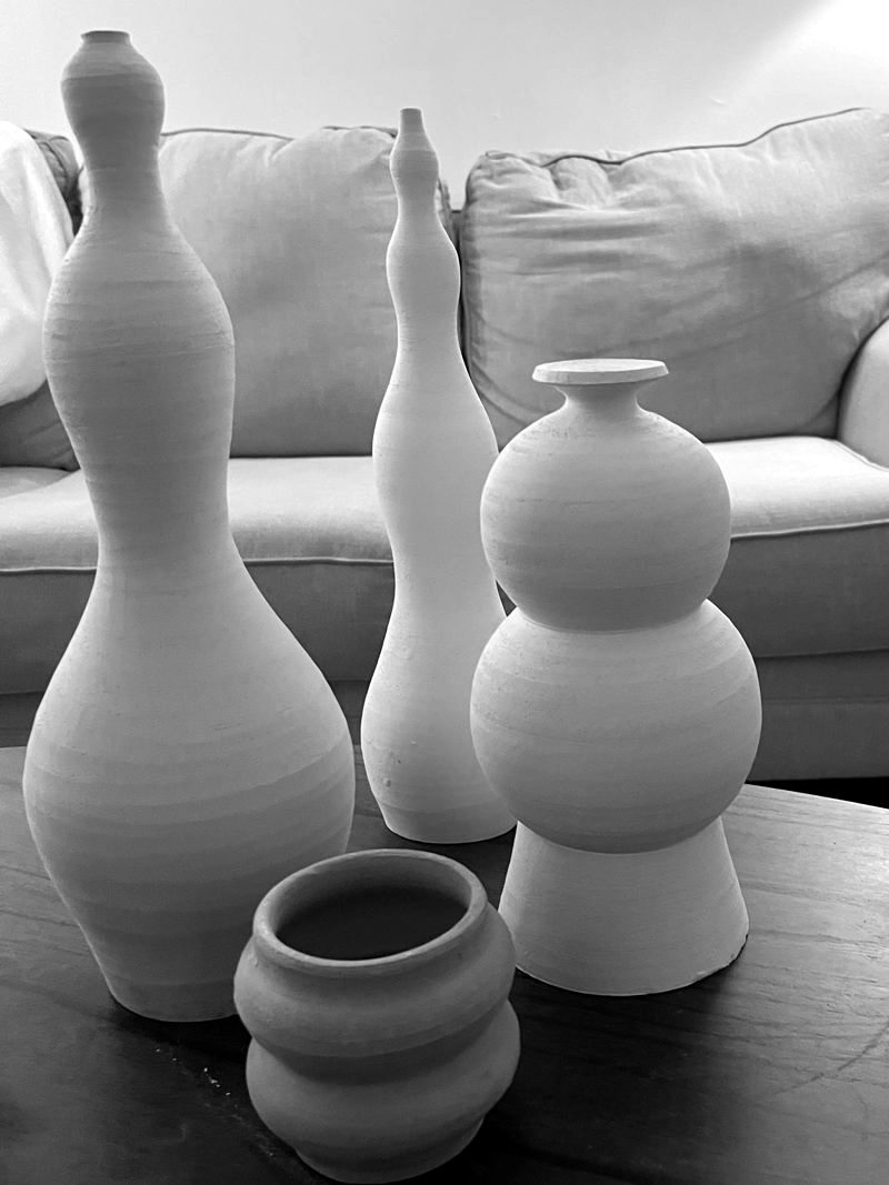 Bisque bottles, vases and a small bowl on a table at home.