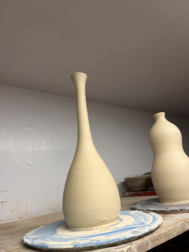 A tall bottle beside a gourd form, drying.